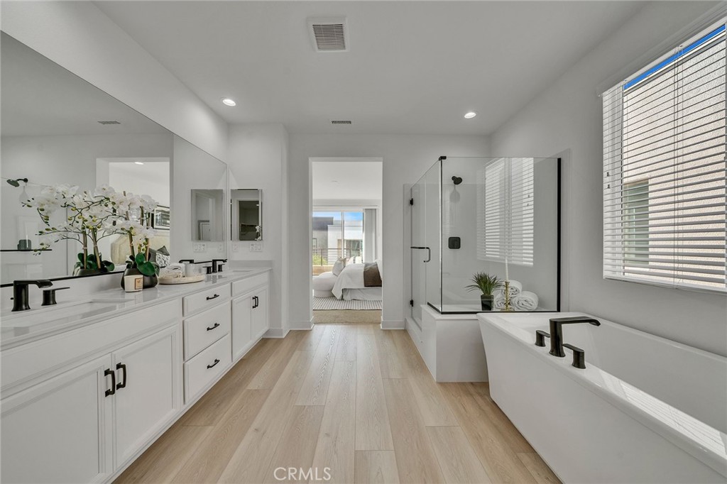 a spacious bathroom with double vanity a large mirror and a bathtub