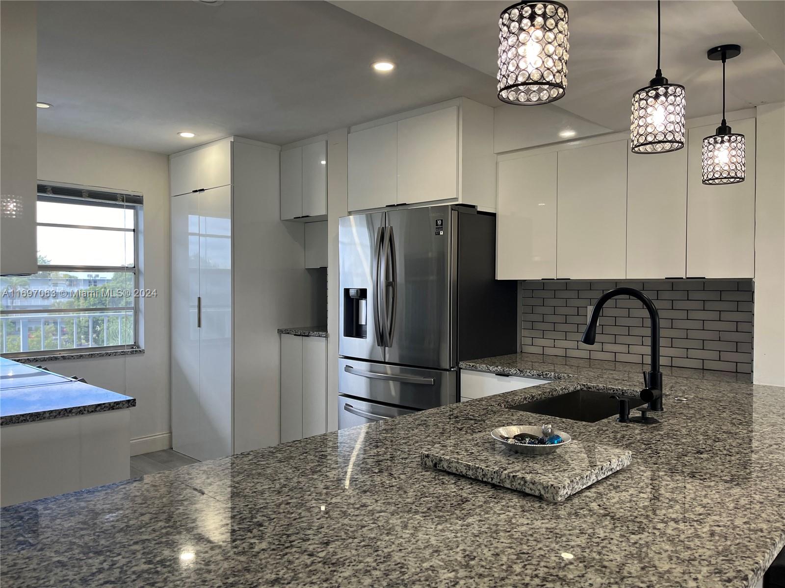 a kitchen with stainless steel appliances granite countertop a refrigerator and a sink