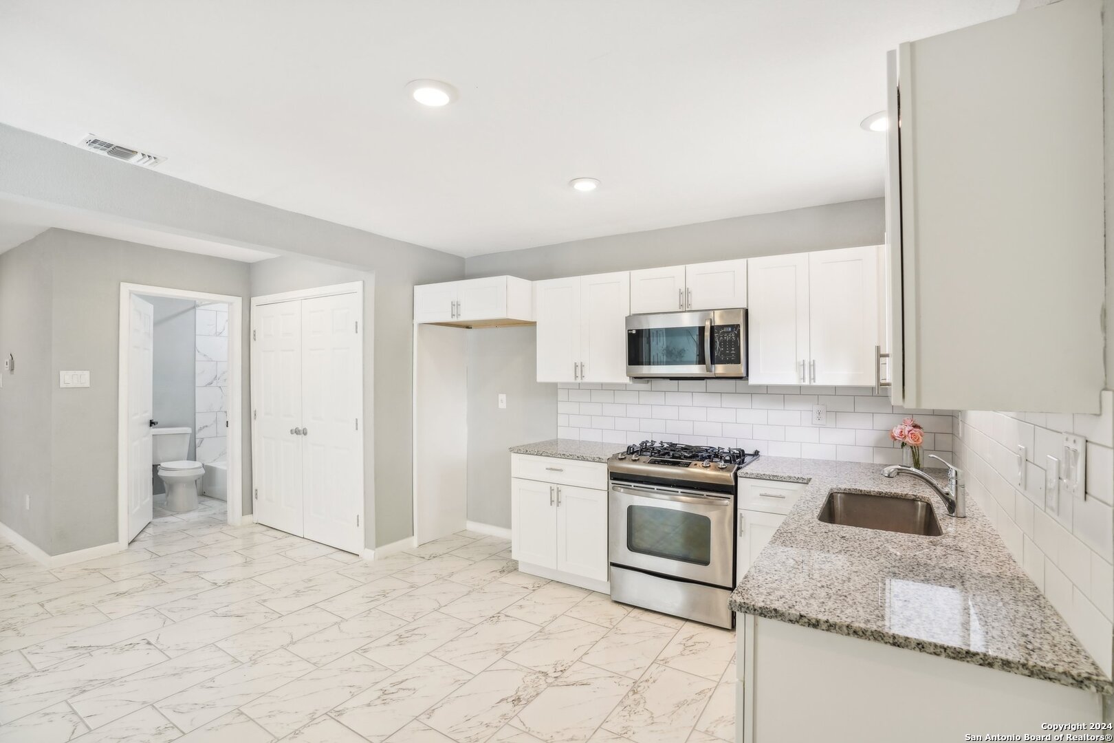 a kitchen with granite countertop a sink a stove and refrigerator