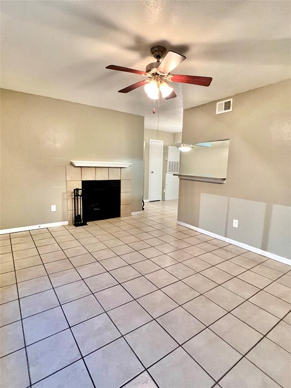 Spacious, well-lit Living Area featuring a cozy corner fireplace in a neutral color scheme. There's a half-wall ledge that could serve as a division or a place for decor, and the room allows for flexible furniture arrangement.