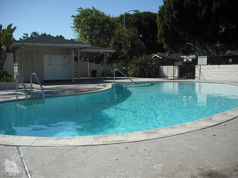 a view of pool with lawn chairs and plants