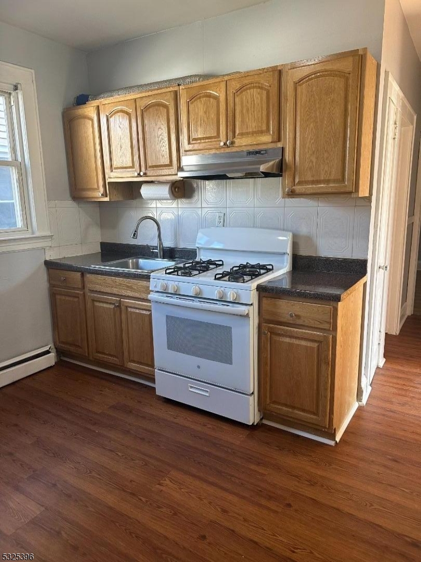 a kitchen with stainless steel appliances granite countertop a stove a sink dishwasher and microwave with wooden floors