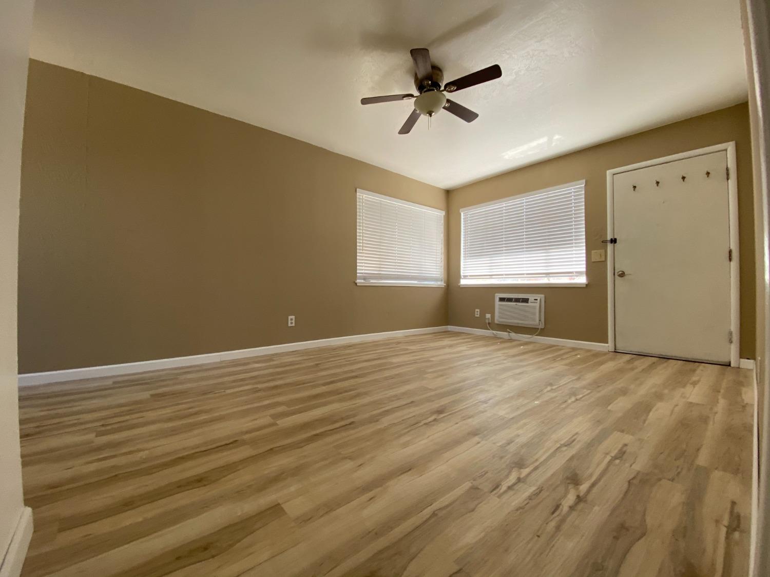 a view of empty room with wooden floor and fan