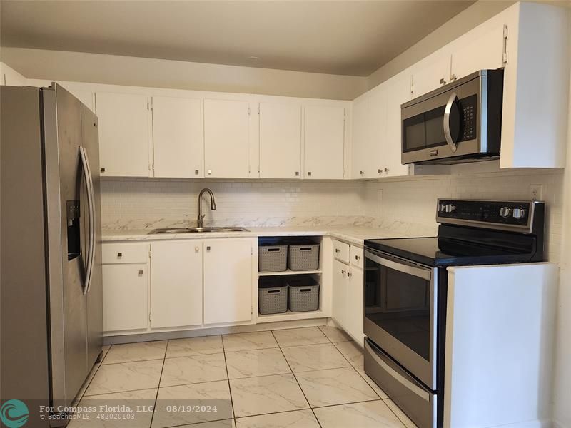 a kitchen with white cabinets and stainless steel appliances