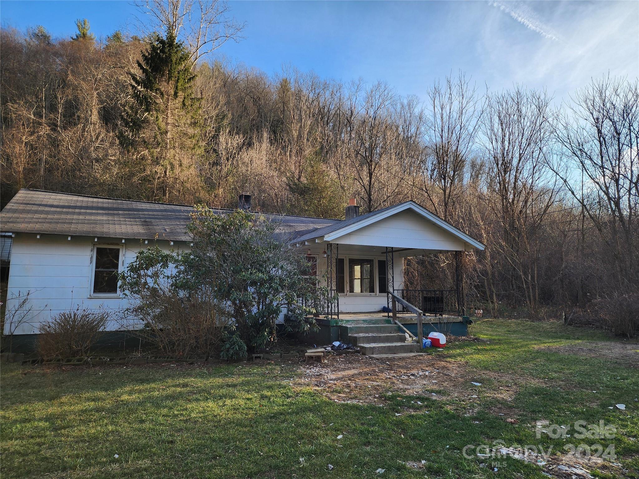 a view of a house with a yard chairs and table in back yard