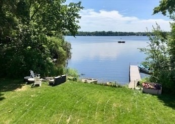 a backyard of a house with lots of green space and lake view