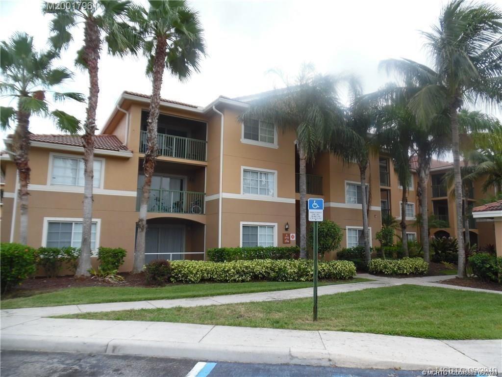 a front view of a residential apartment building with a yard and palm trees