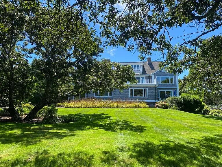 a view of a house with a big yard and large trees