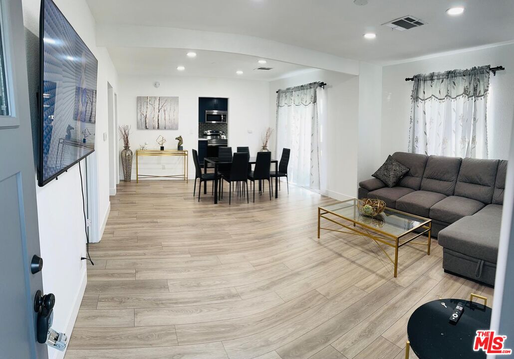 a living room with furniture and a dining table with wooden floor