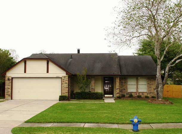 a front view of a house with a garden and trees