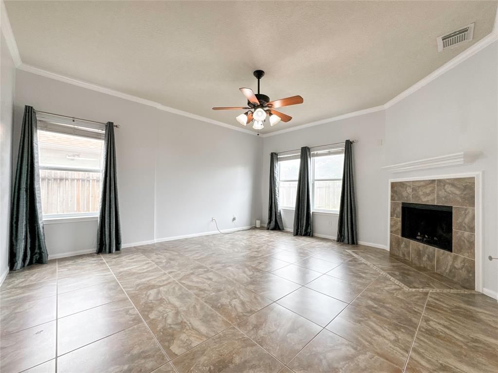 a view of an empty room with chandelier fan and fire place