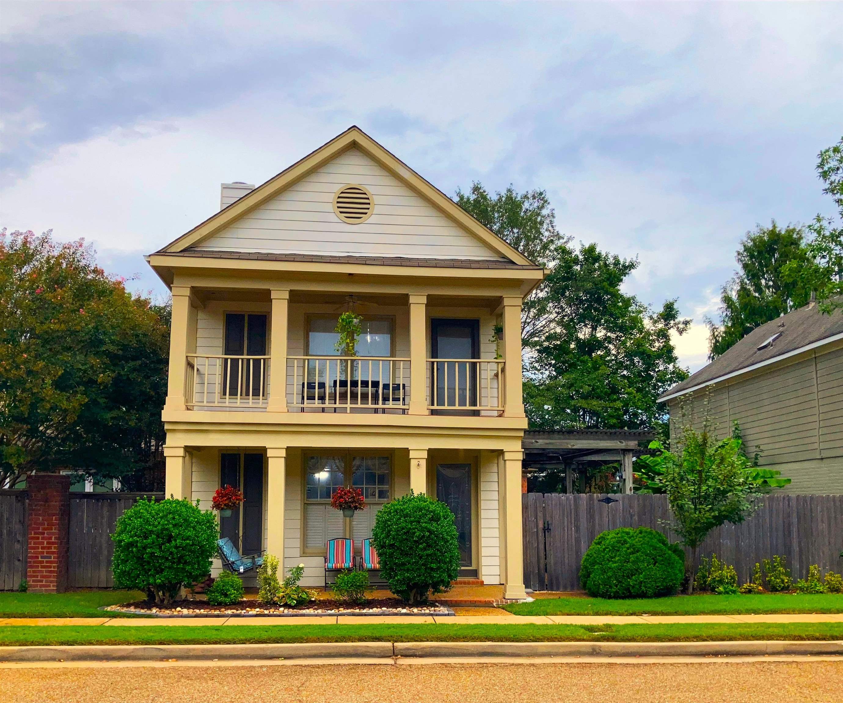 Greek revival house featuring a balcony, a porch, and a front lawn