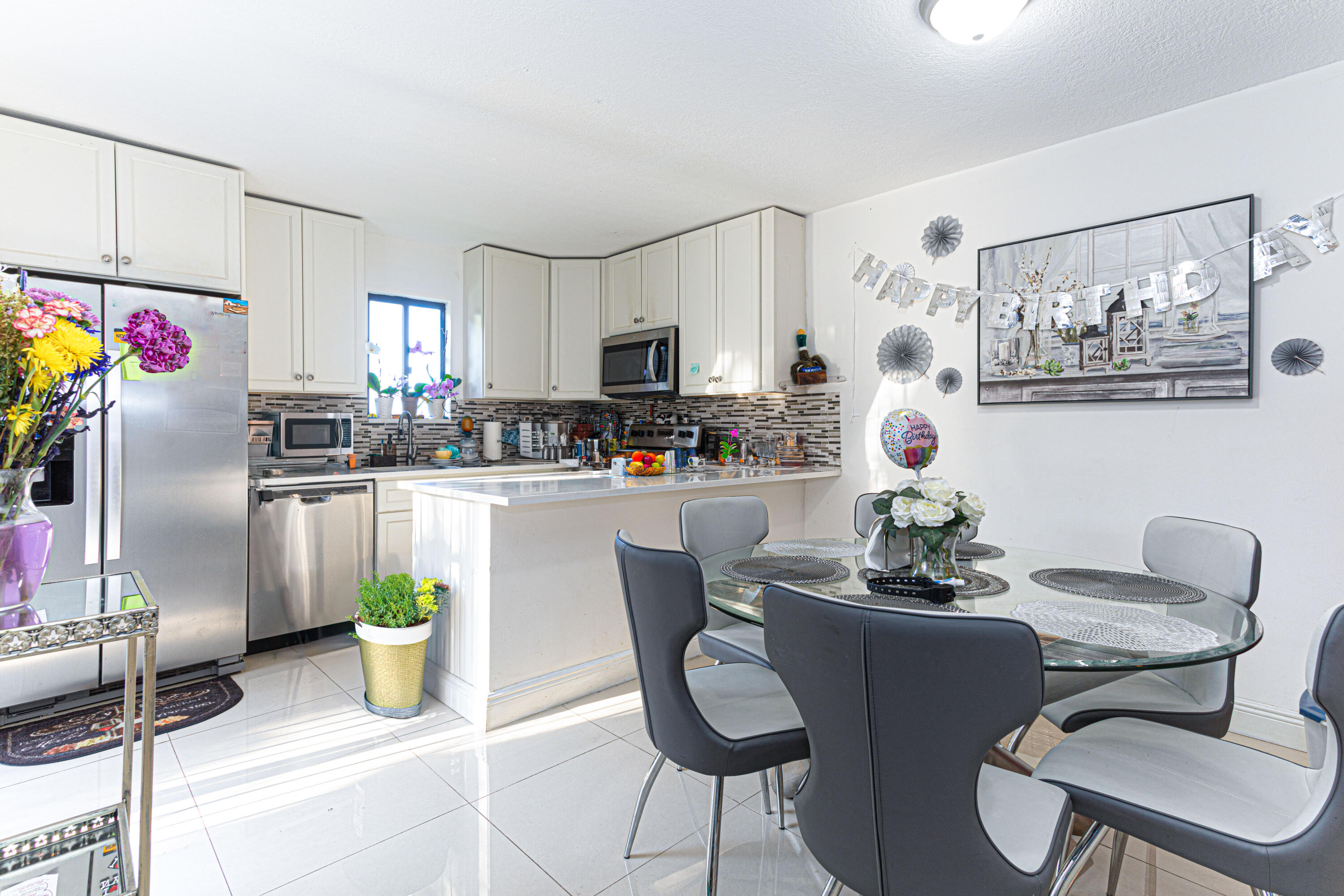 a kitchen with stainless steel appliances a dining table chairs and refrigerator