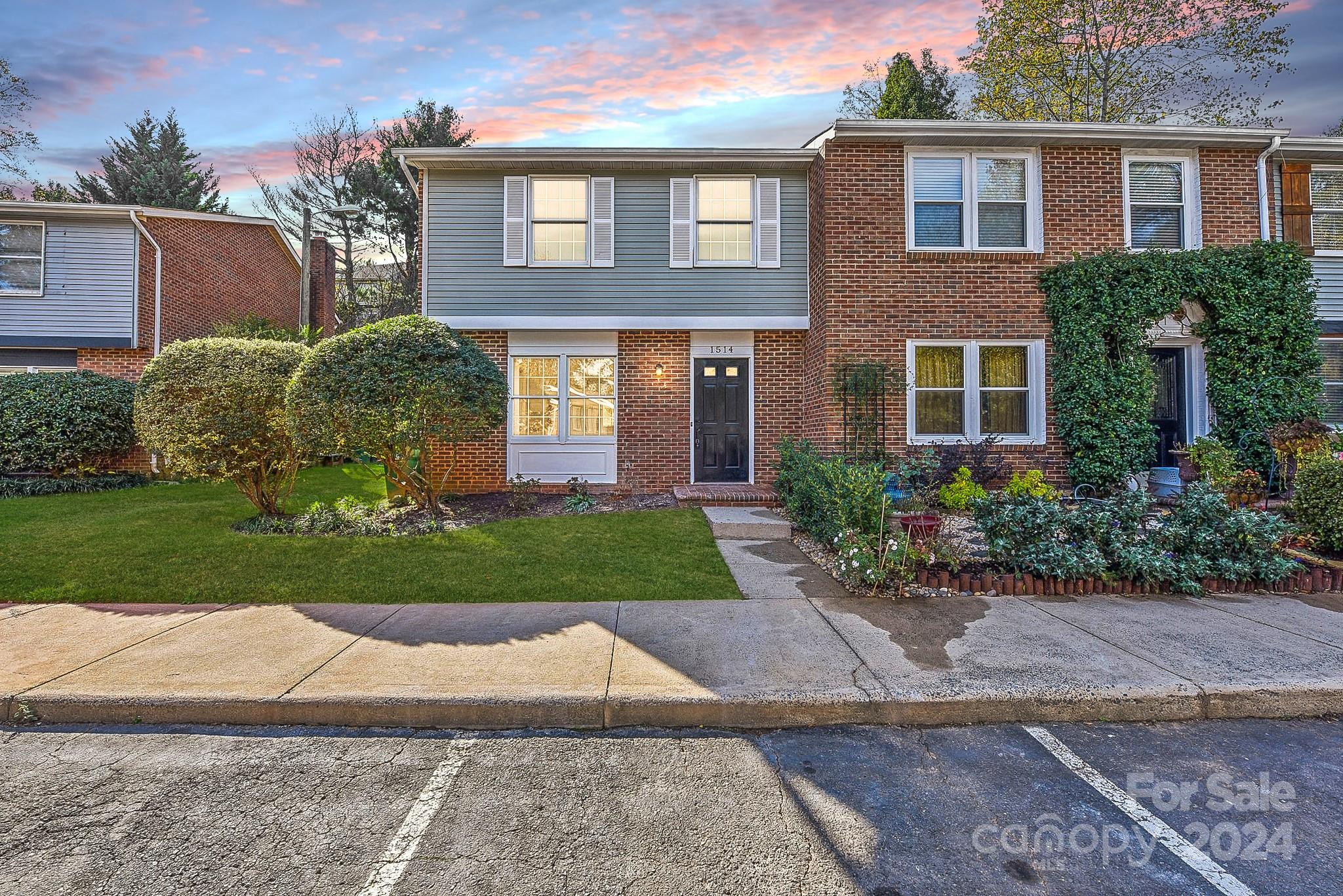 a view of a brick house with a yard and plants