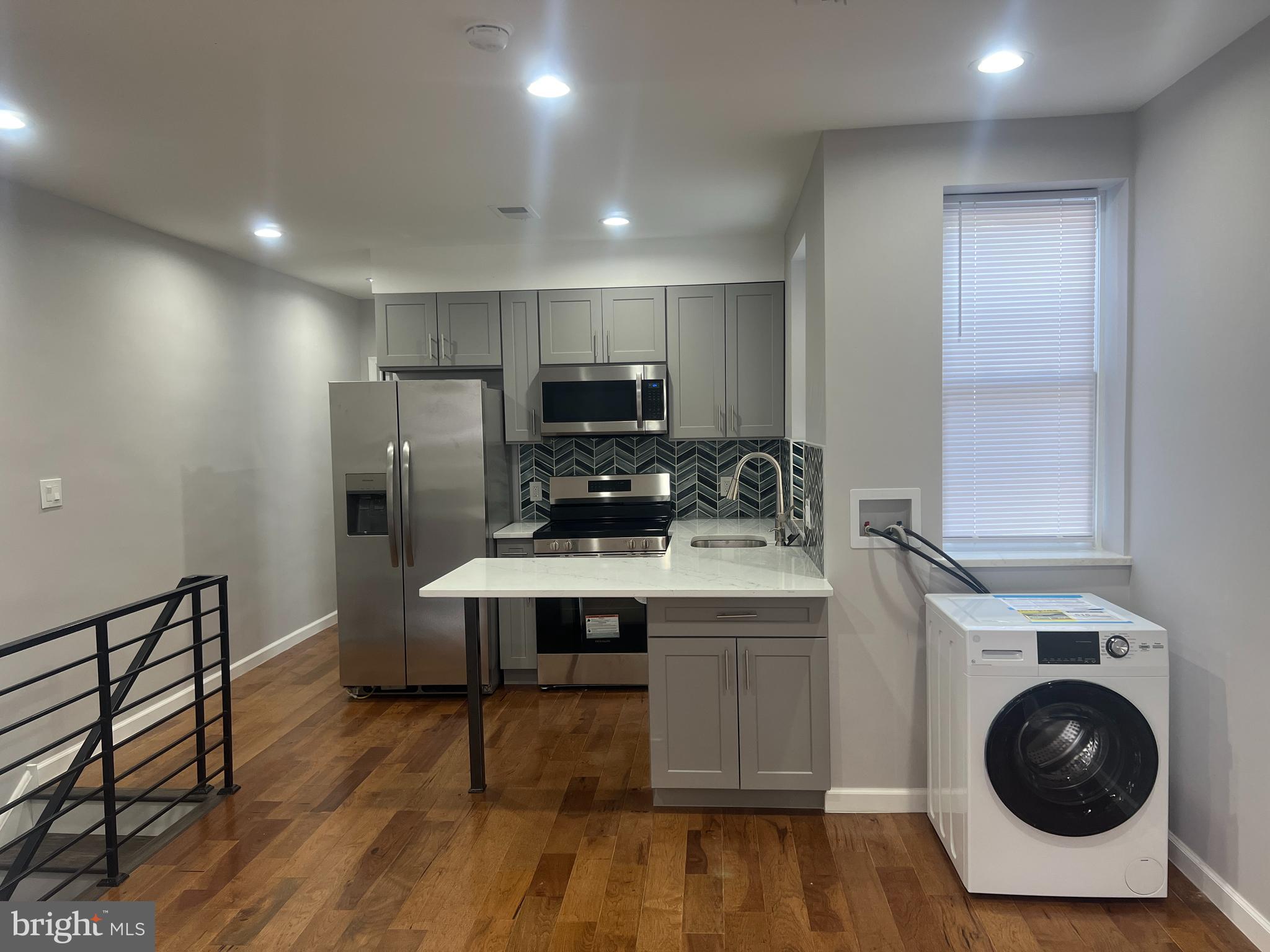 a kitchen with a sink a refrigerator and wooden floor