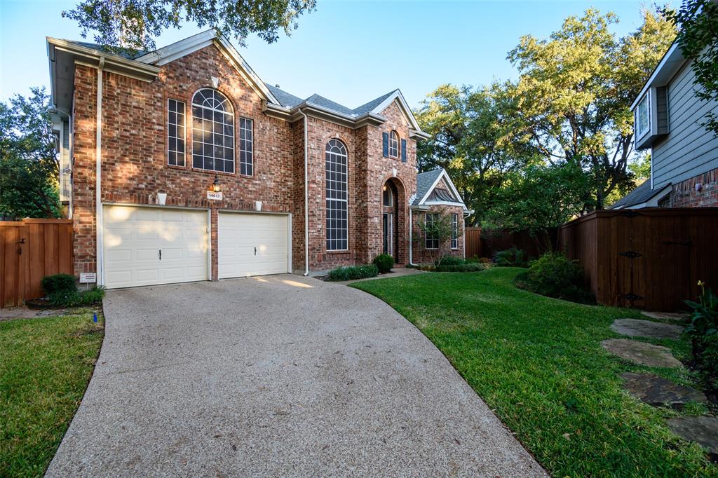 a view of a house with brick walls plants and large tree