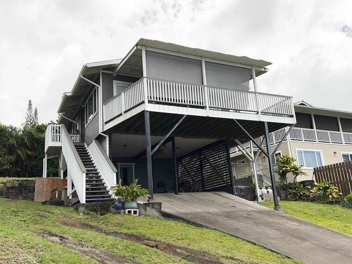 Driveway entering carport with the expansive deck above.  The stairs lead to main entrance of the upper level with 3 bedrooms and 1 bathroom.