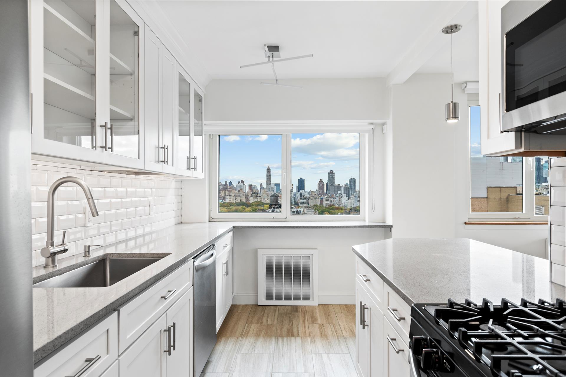 a kitchen with a sink appliances cabinets and a large window