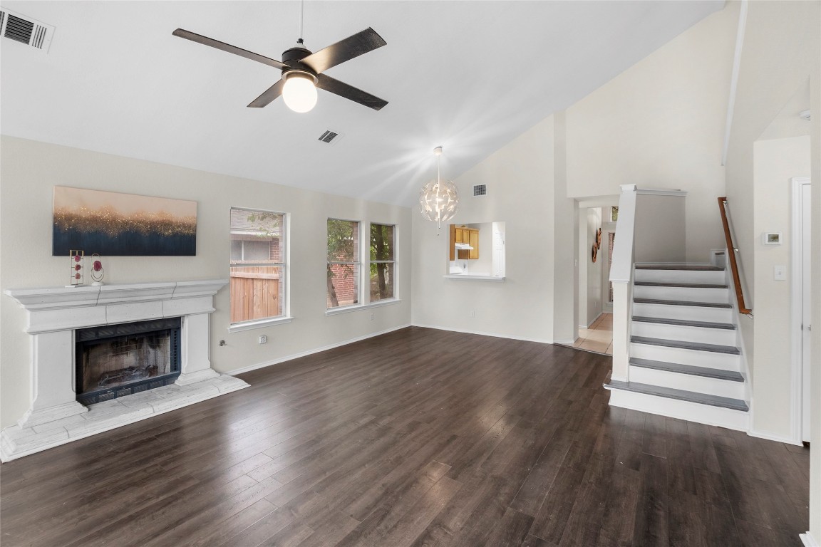 a view of an empty room with wooden floor fireplace and a window