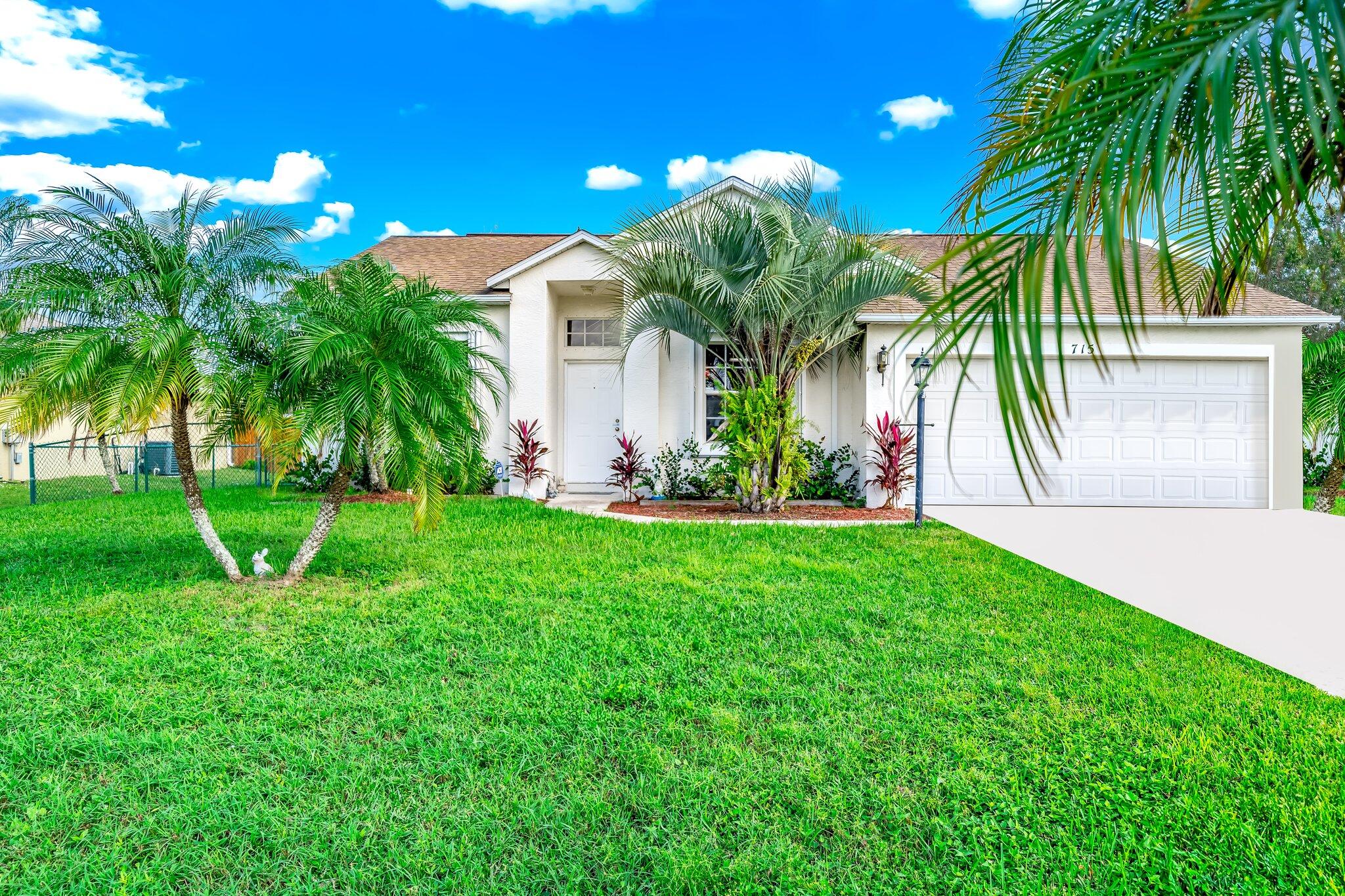 a view of a house with a yard and palm trees