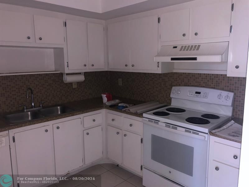 a kitchen with granite countertop white cabinets and white appliances