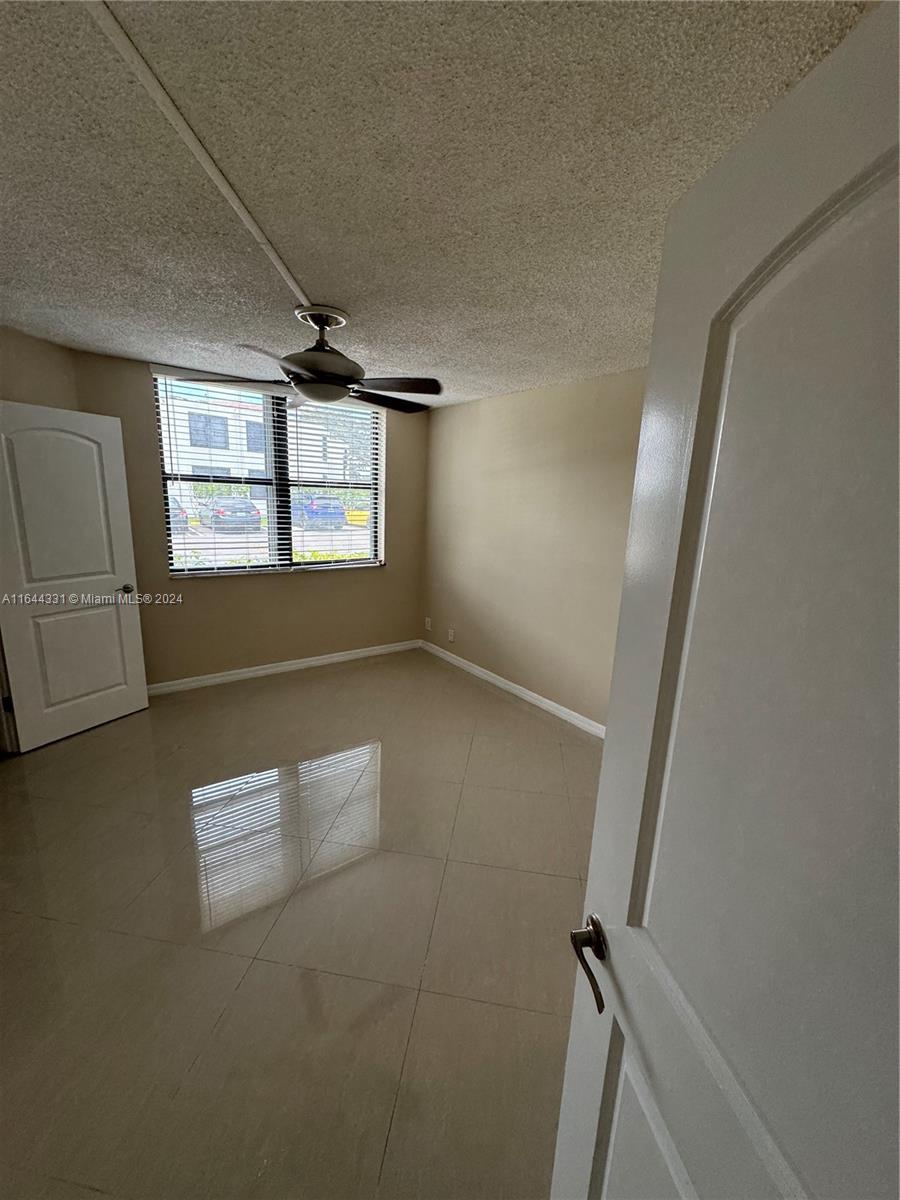 an empty room with windows and ceiling fan