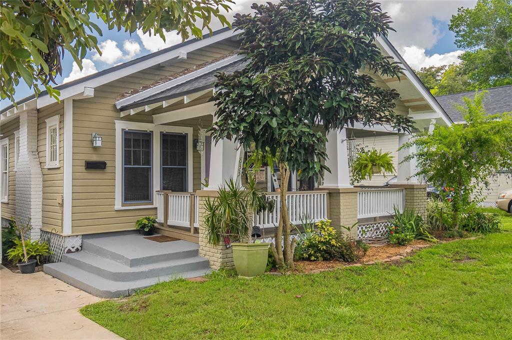 a front view of a house with a yard and potted plants