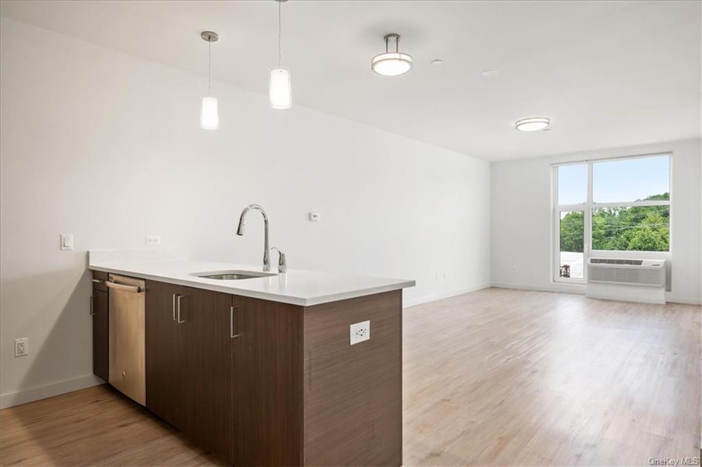 Kitchen featuring light hardwood / wood-style floors, sink, kitchen peninsula, pendant lighting, and dark brown cabinetry