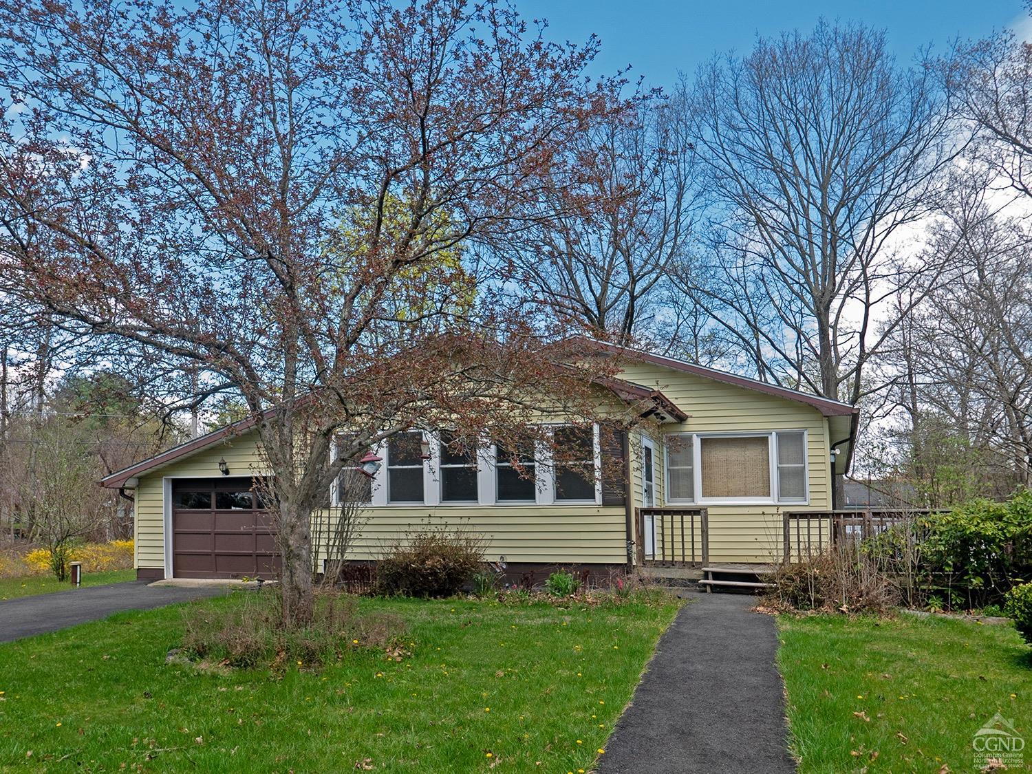 a front view of a house with a garden and trees