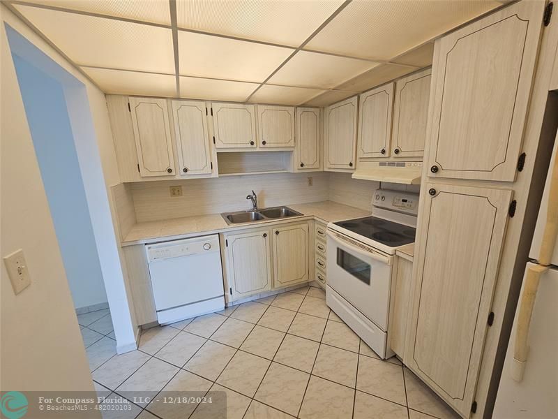 a kitchen with white cabinets a sink dishwasher and a stove with wooden floor