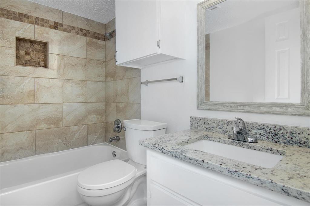 a bathroom with a granite countertop sink a toilet and bathtub