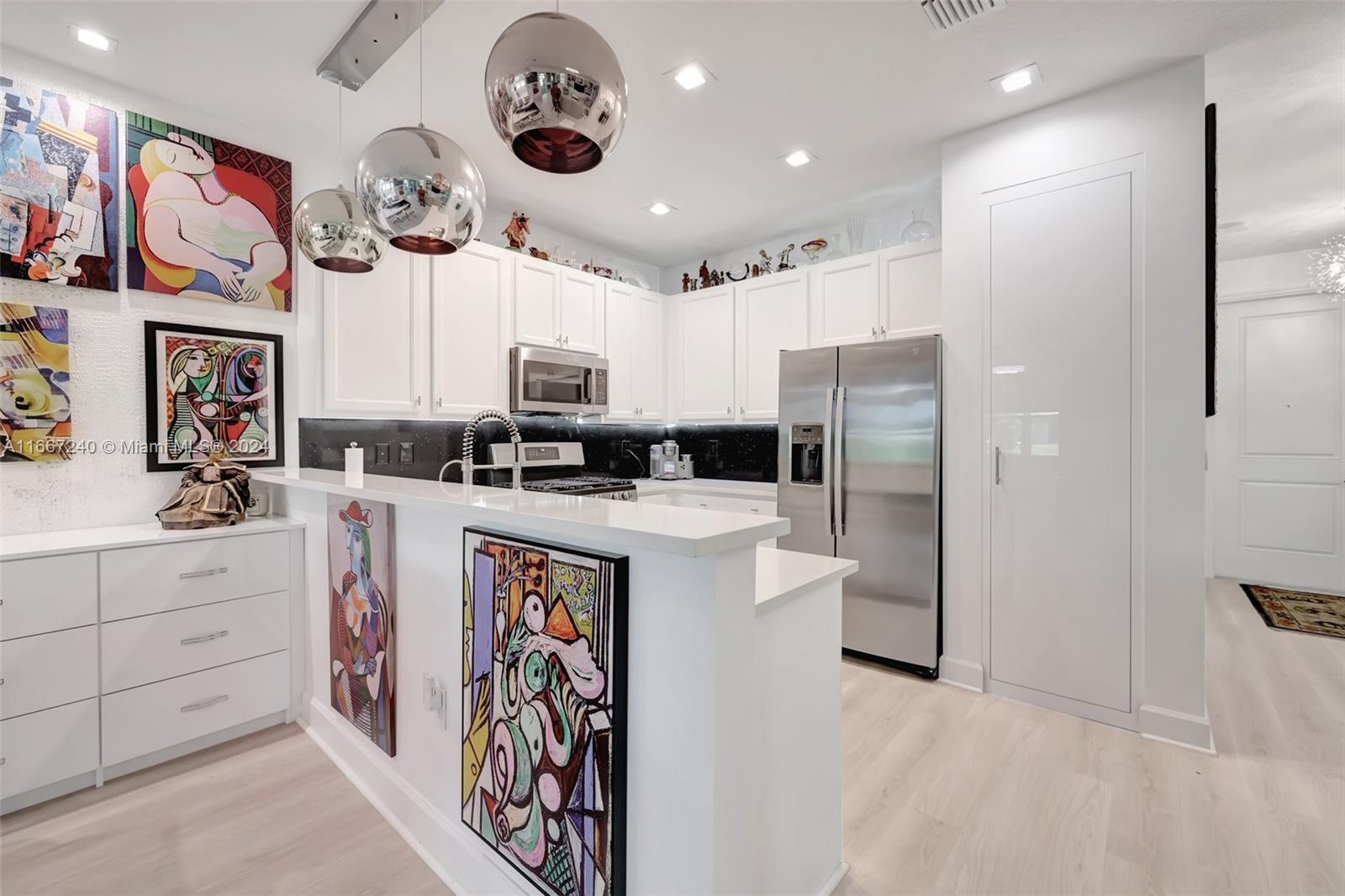 a kitchen with a refrigerator a sink and dishwasher with white cabinets