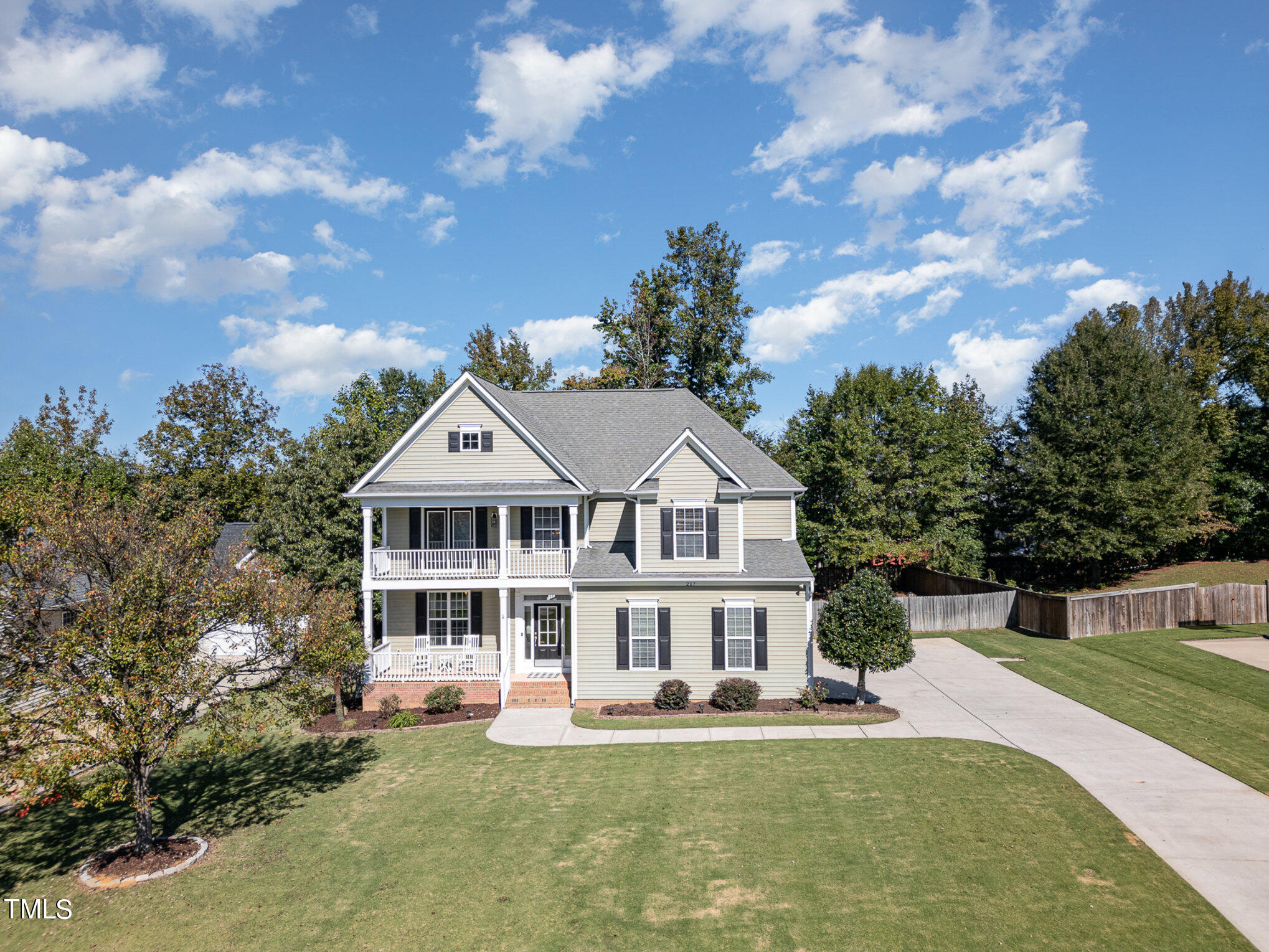 a front view of a house with a garden and trees