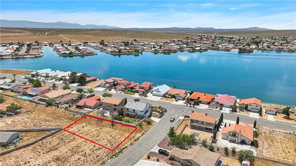 an aerial view of ocean and residential houses with outdoor space