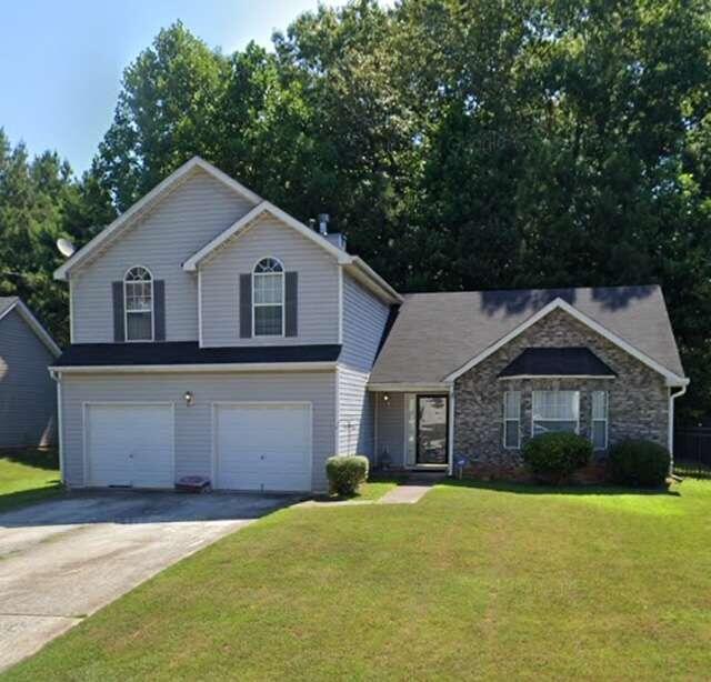 a front view of a house with a garden and yard