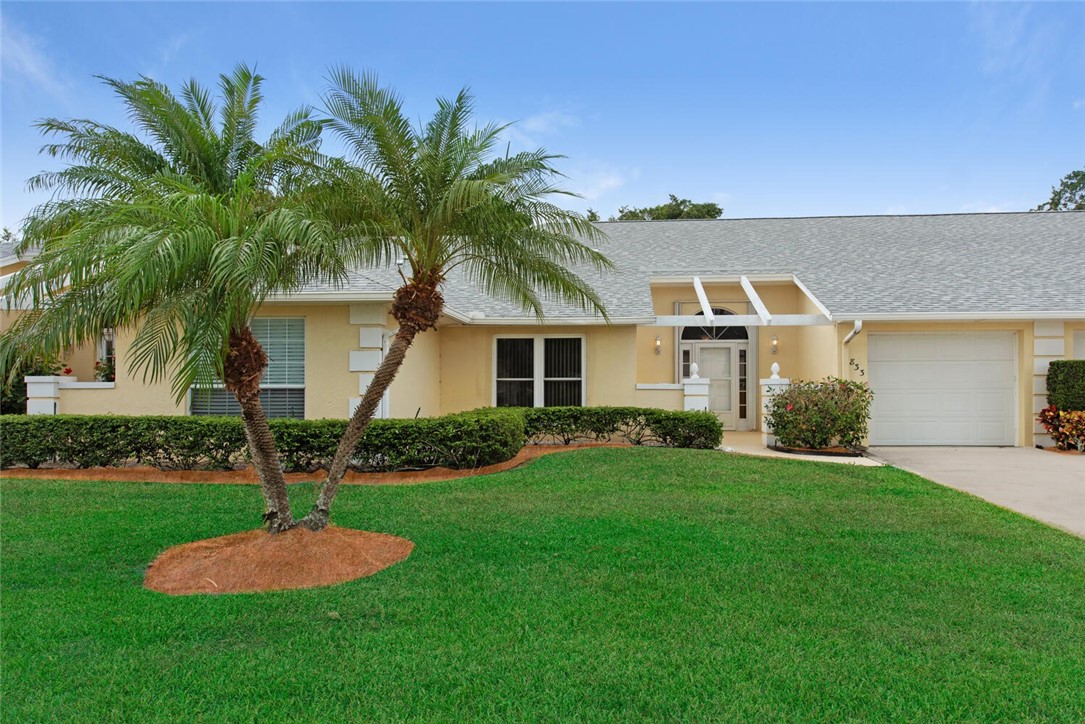 a front view of a house with a yard and palm tree