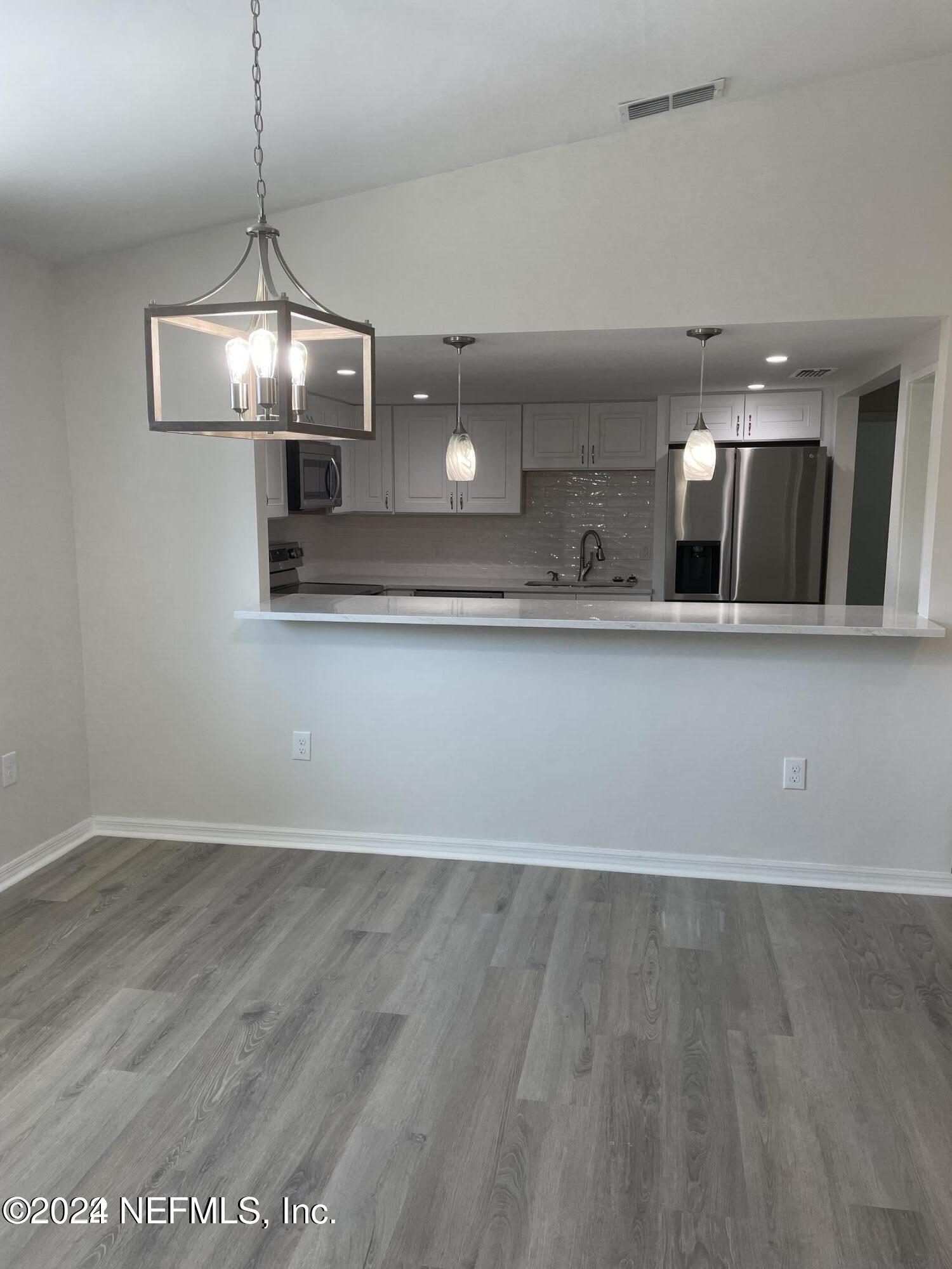 a view of a room with wooden floor and chandelier