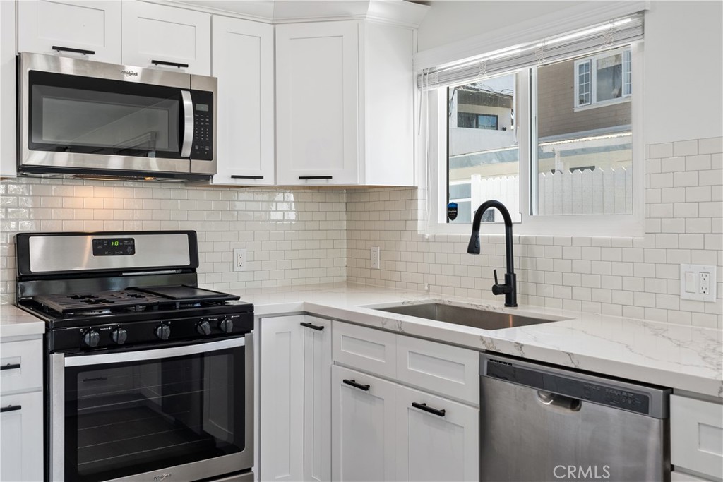 a kitchen with stainless steel appliances a stove a microwave a sink and cabinets