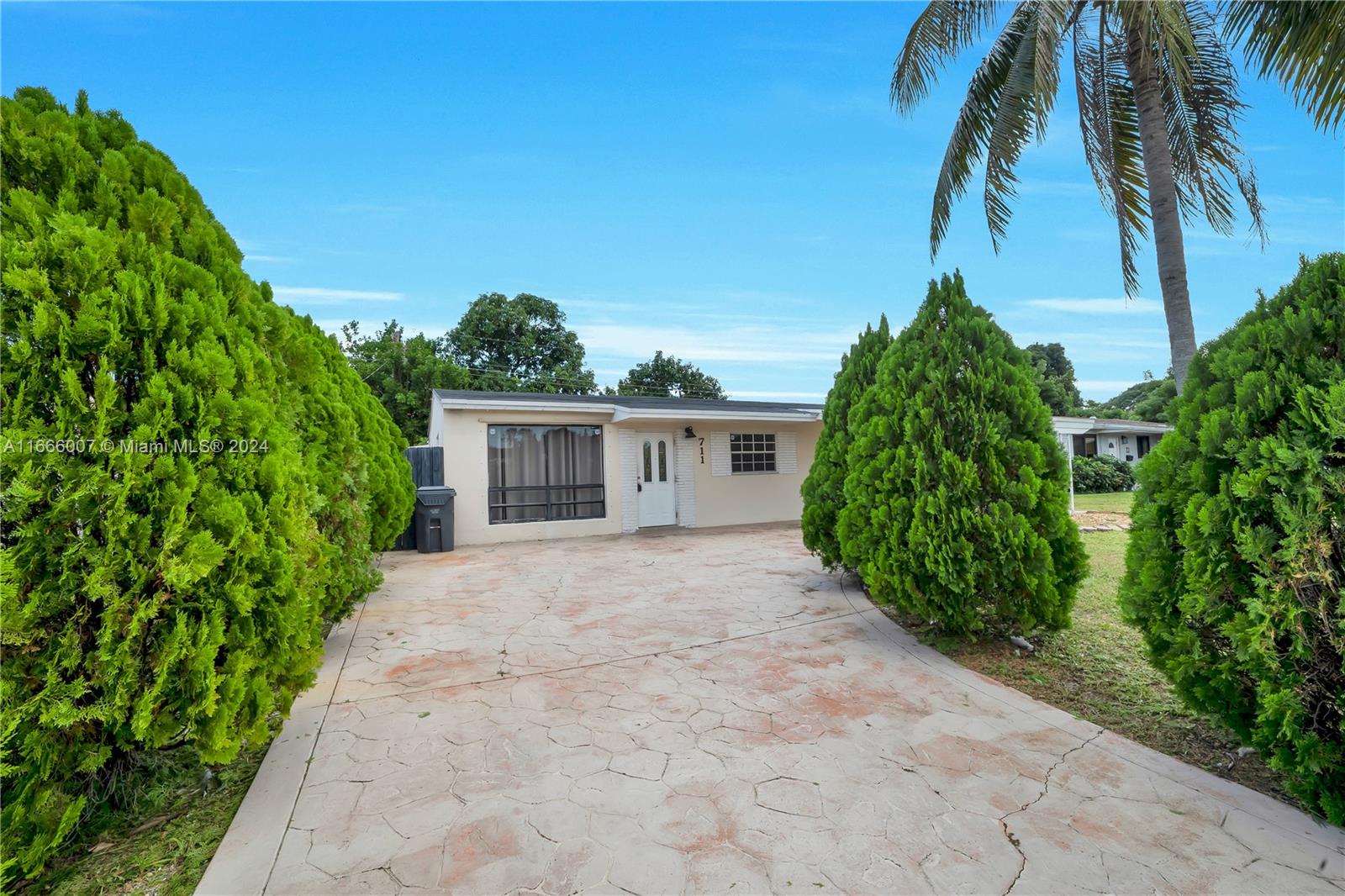 a view of a house with a yard and palm trees