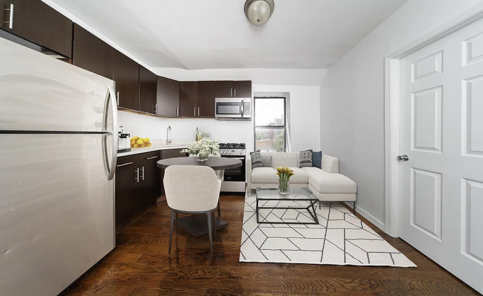 a living room with furniture a table and kitchen view