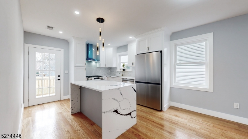 a kitchen with kitchen island white cabinets and refrigerator