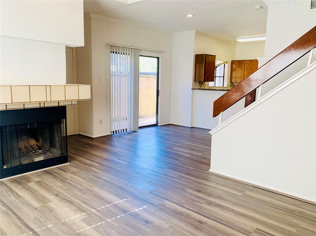 a view of an empty room with wooden floor fireplace and a window