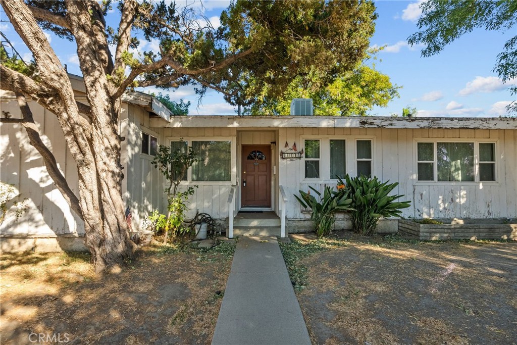 a view of house with yard outdoor seating and covered with trees