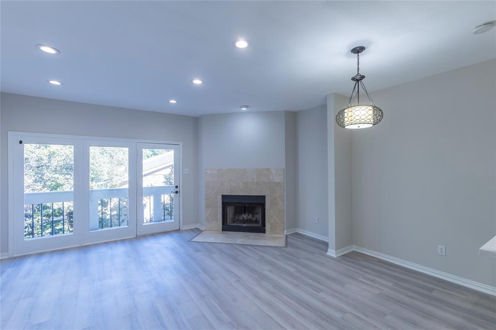 an empty room with wooden floor fireplace and windows