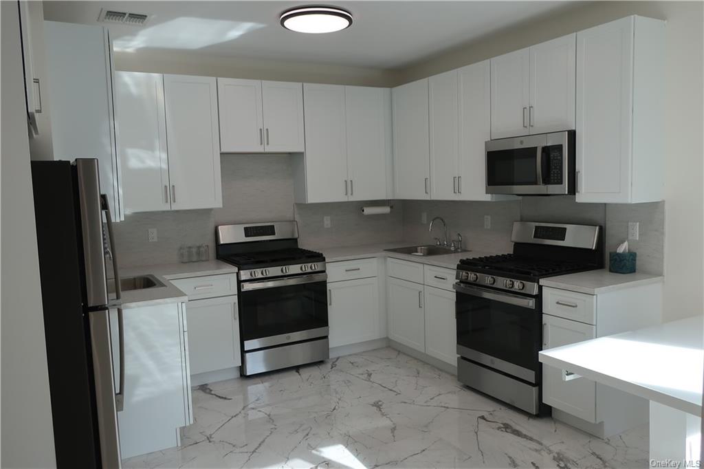 a kitchen with granite countertop white cabinets and stainless steel appliances