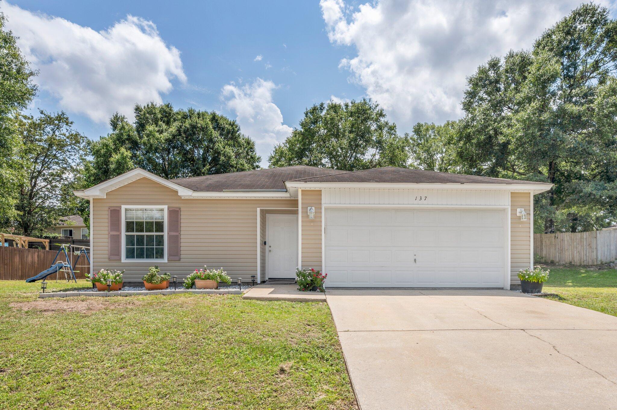 a front view of house with yard and trees in the background