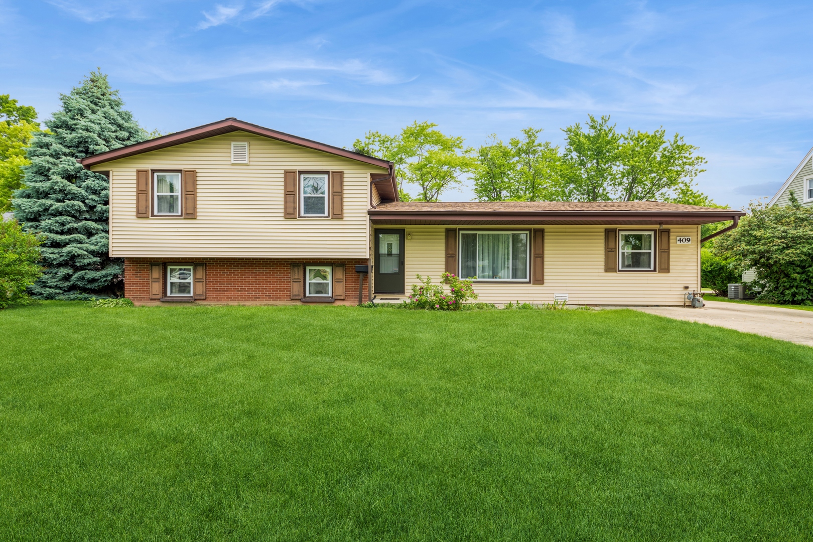 a front view of a house with a yard and green space