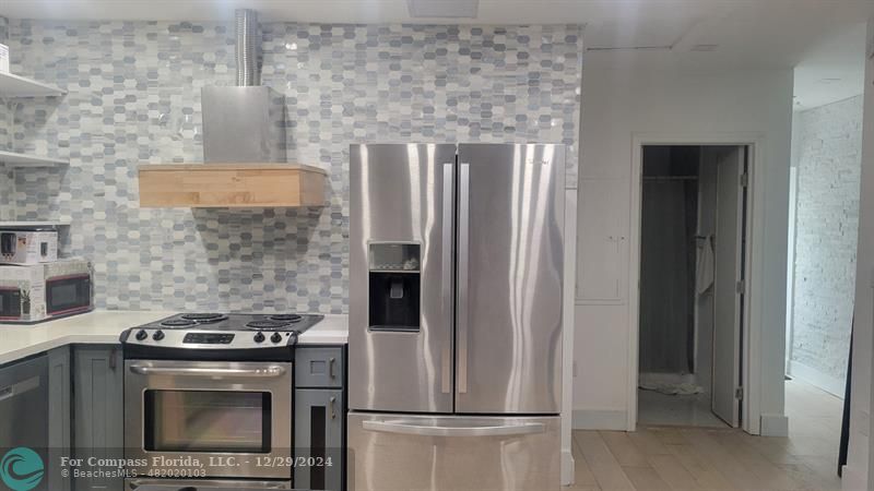 a kitchen with stainless steel appliances granite countertop a refrigerator and a stove top oven