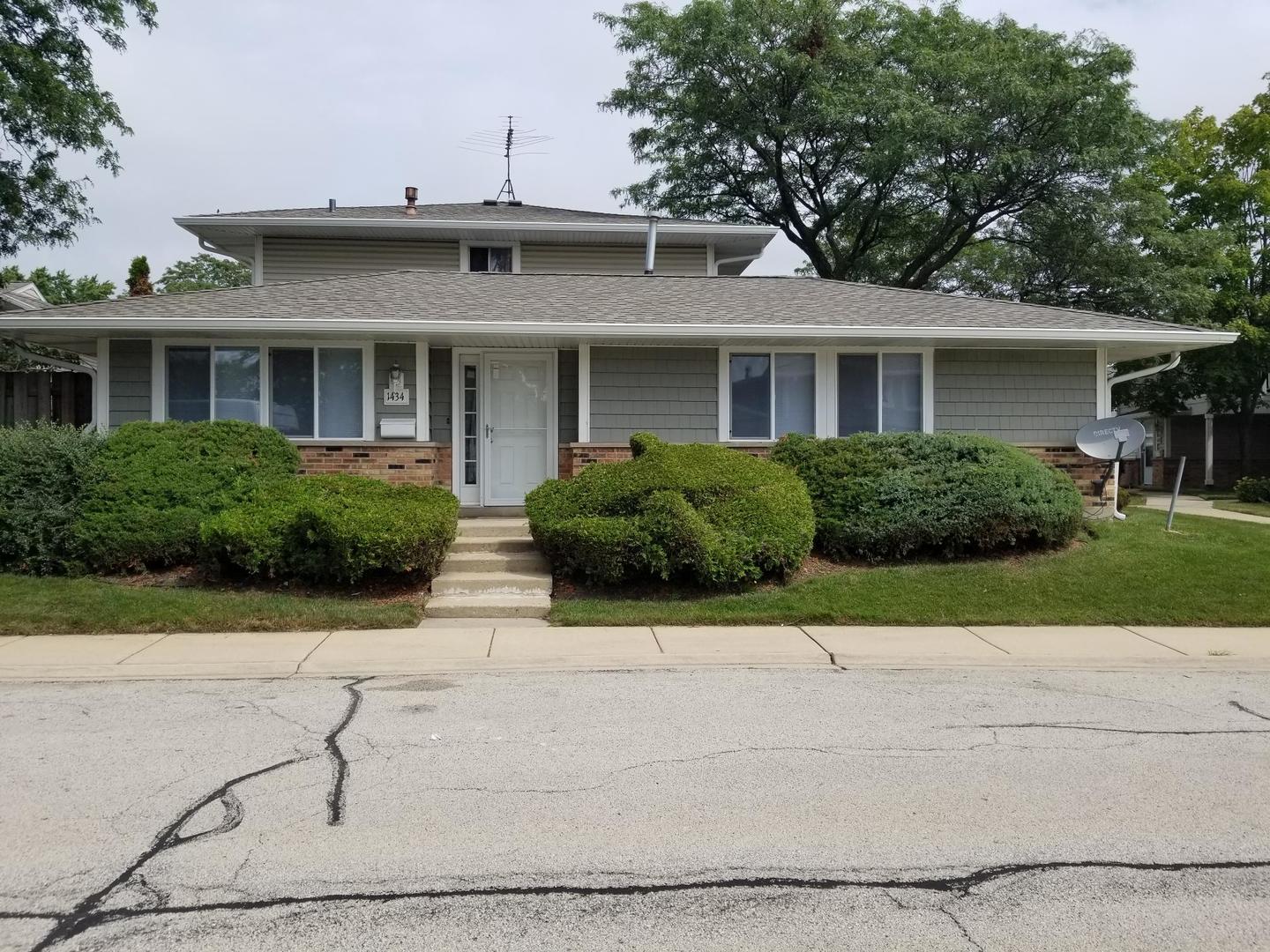 a front view of a house with garage and plants