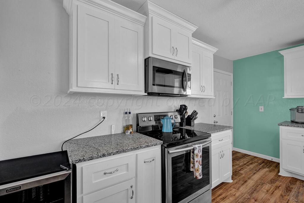 a kitchen with granite countertop white cabinets and black appliances